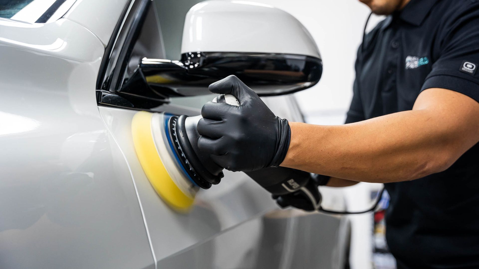 A man is polishing a car with a machine.