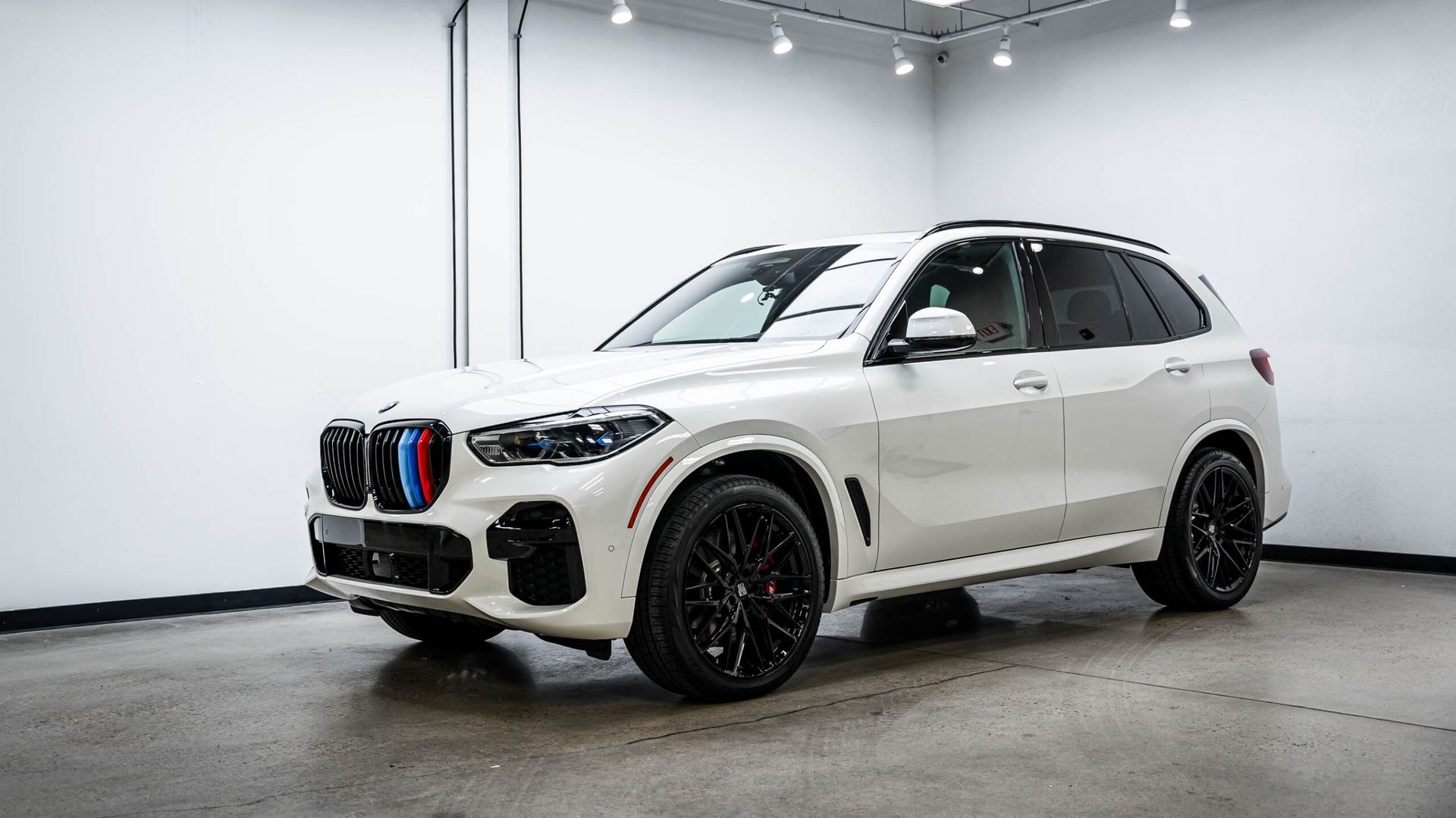 A white bmw x5 is parked in a showroom.