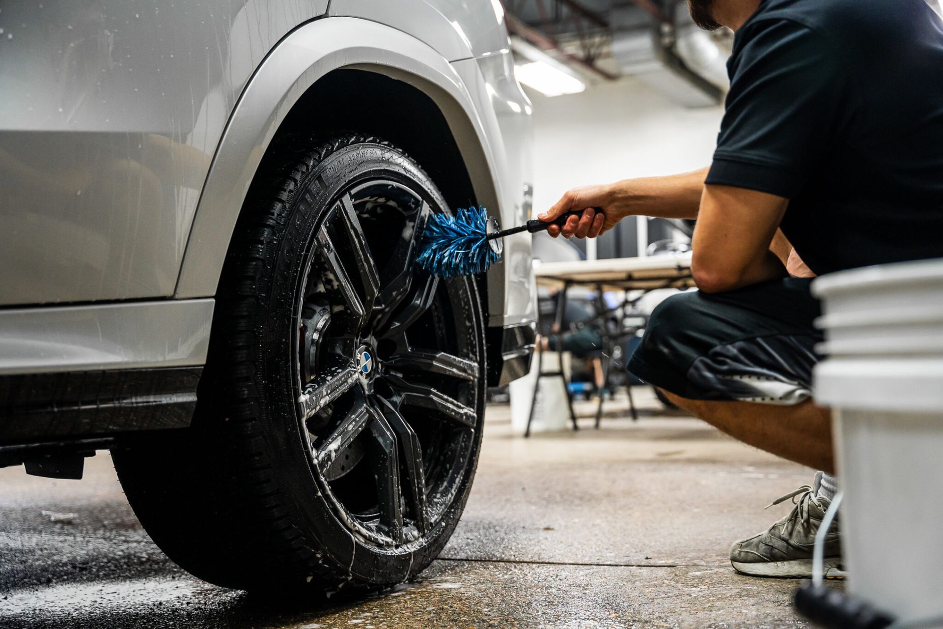 A man is cleaning a car wheel with a brush.