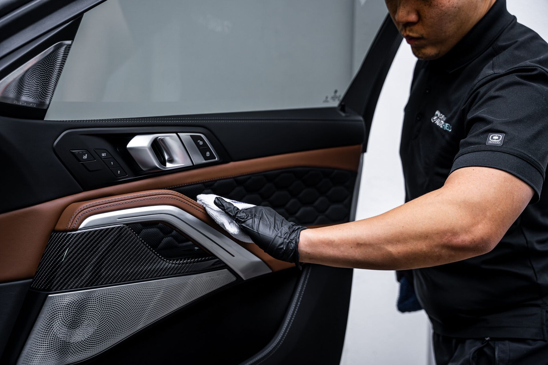 A man is cleaning the door handle of a car.