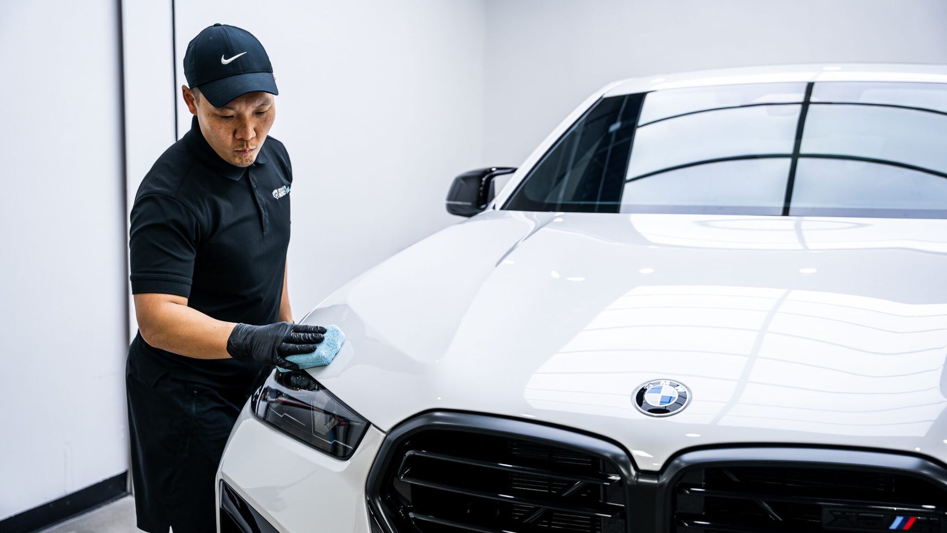 A man is cleaning a white car with a cloth.