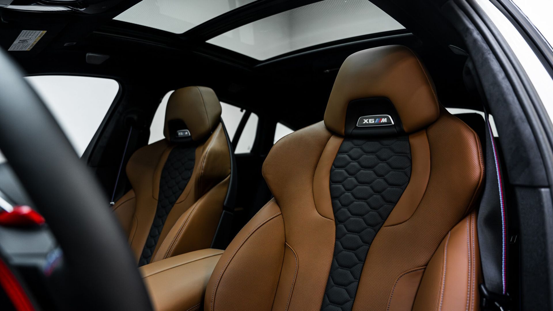 The interior of a car with brown leather seats and a sunroof.