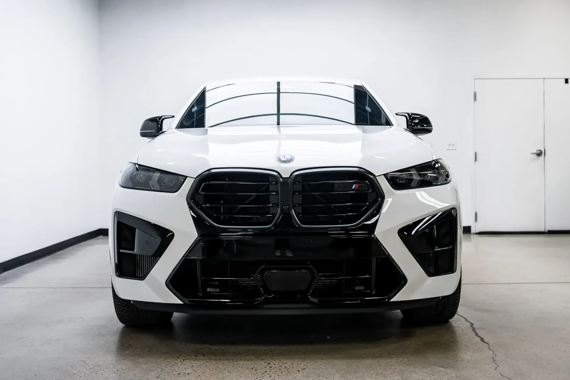 A white bmw m4 is parked in a garage.