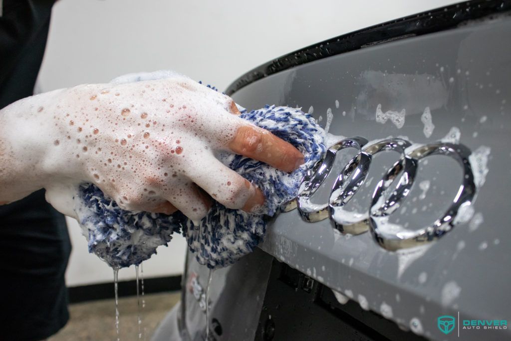 A person is washing a car with a towel and soap.