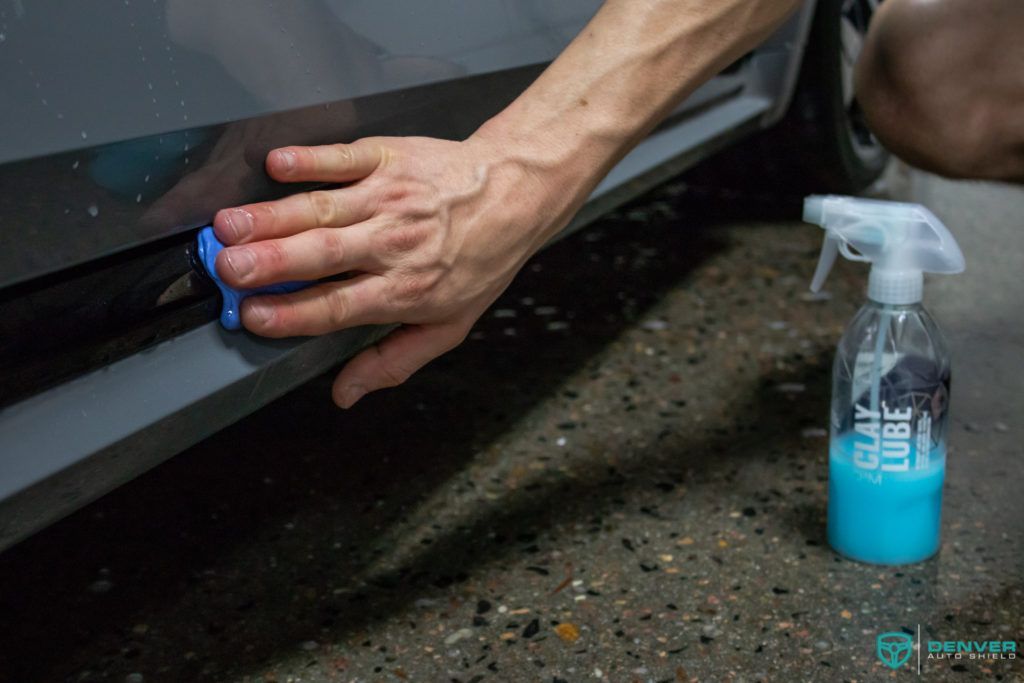 A person is cleaning a car with a sponge and a spray bottle.