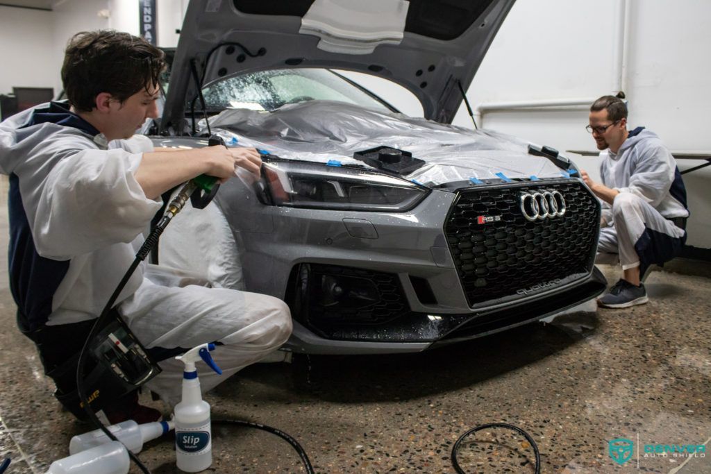 Two men are working on a car in a garage.