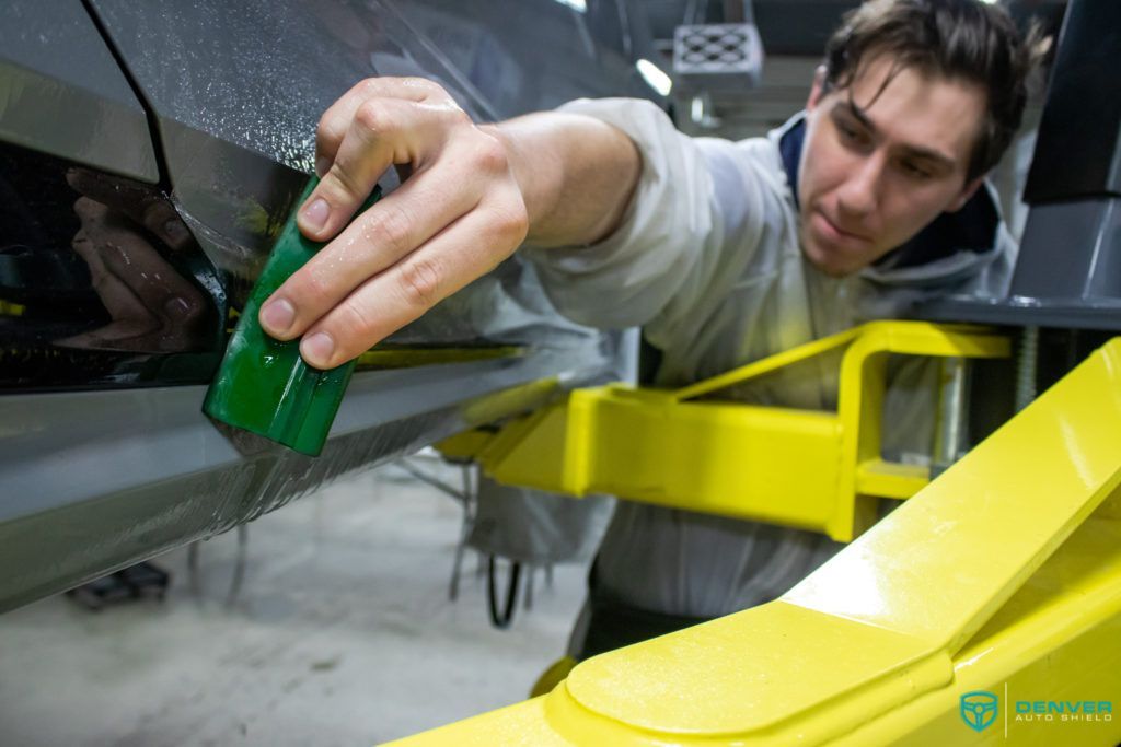 A man is working on a car on a lift in a garage.