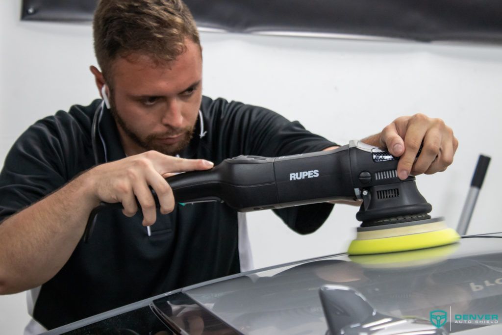 A man is polishing a car with a machine.