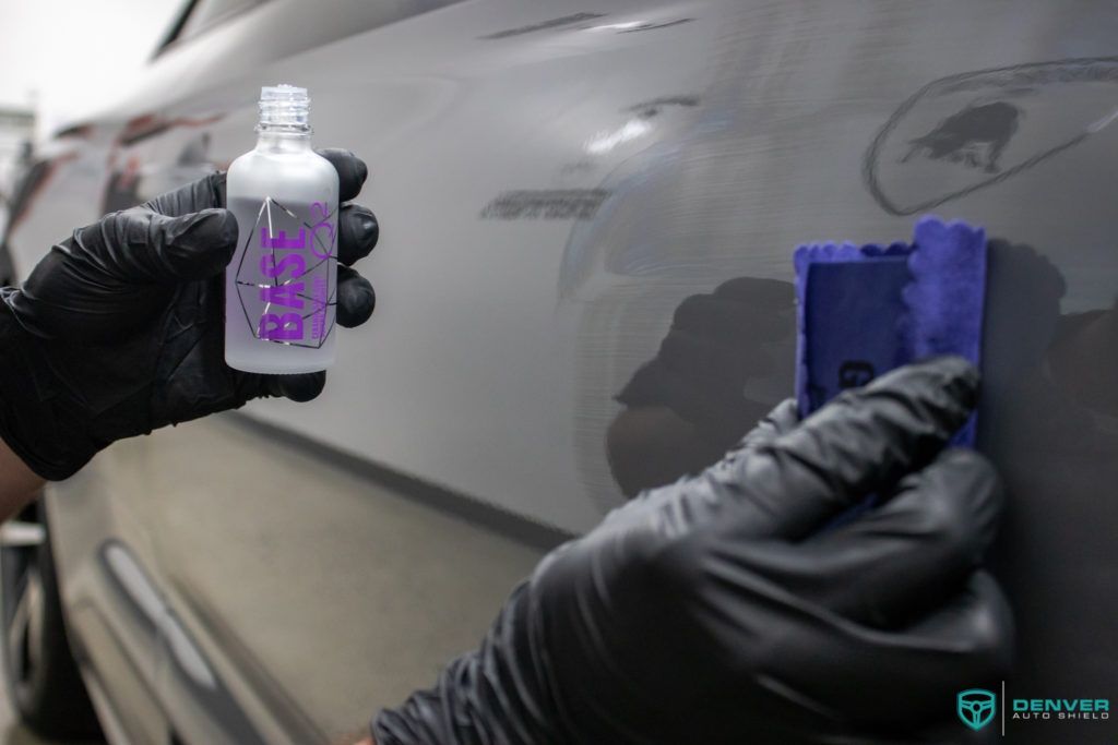 A person wearing black gloves is holding a bottle of ceramic coating.