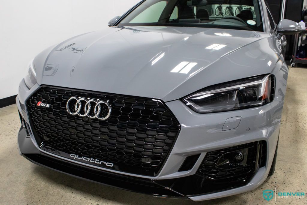 A grey audi rs 5 is parked in a showroom.