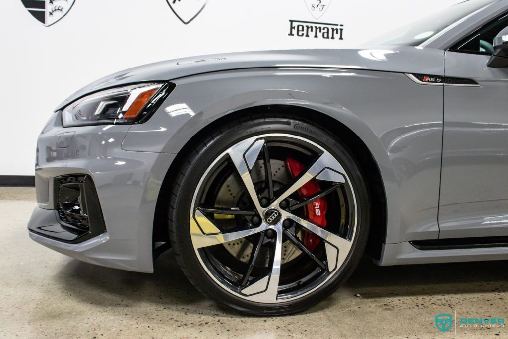 A close up of a gray audi rs5 with red brake calipers.