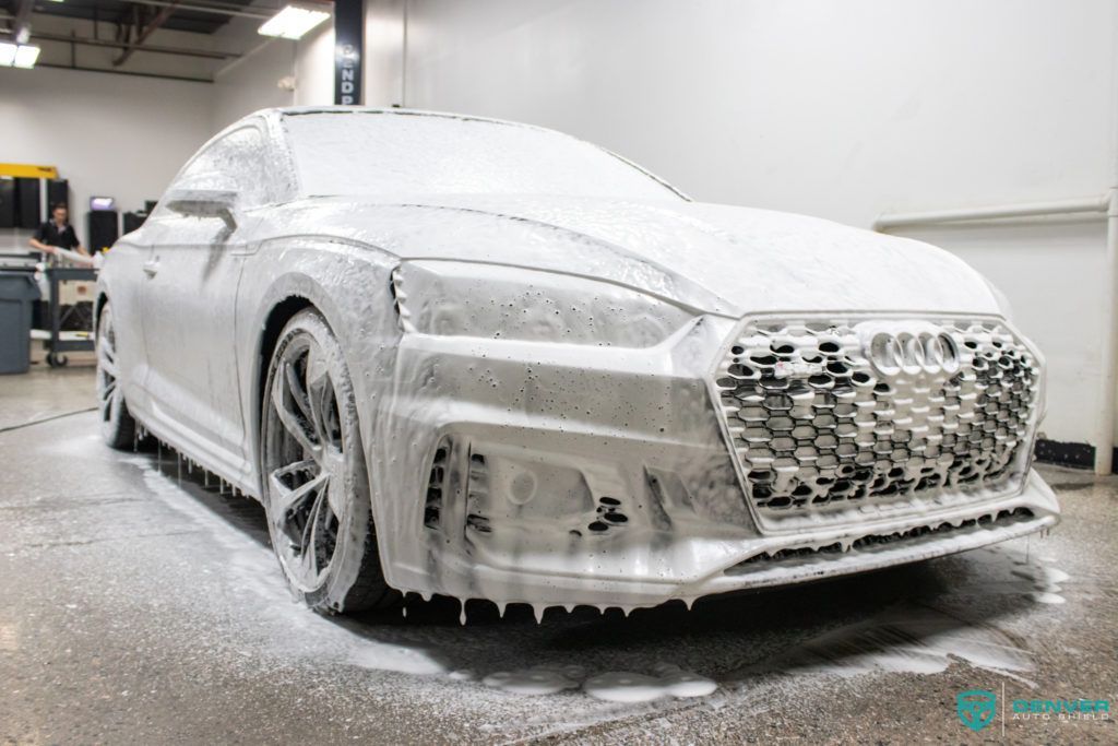 A white car is covered in foam in a garage.