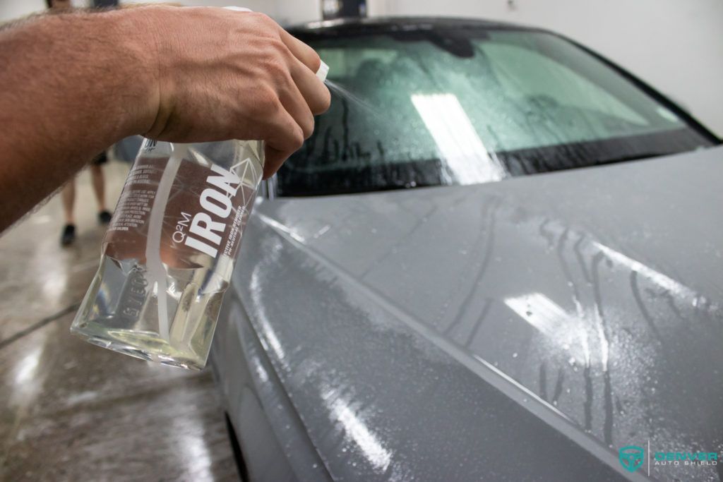 A person is spraying a car with a spray bottle.