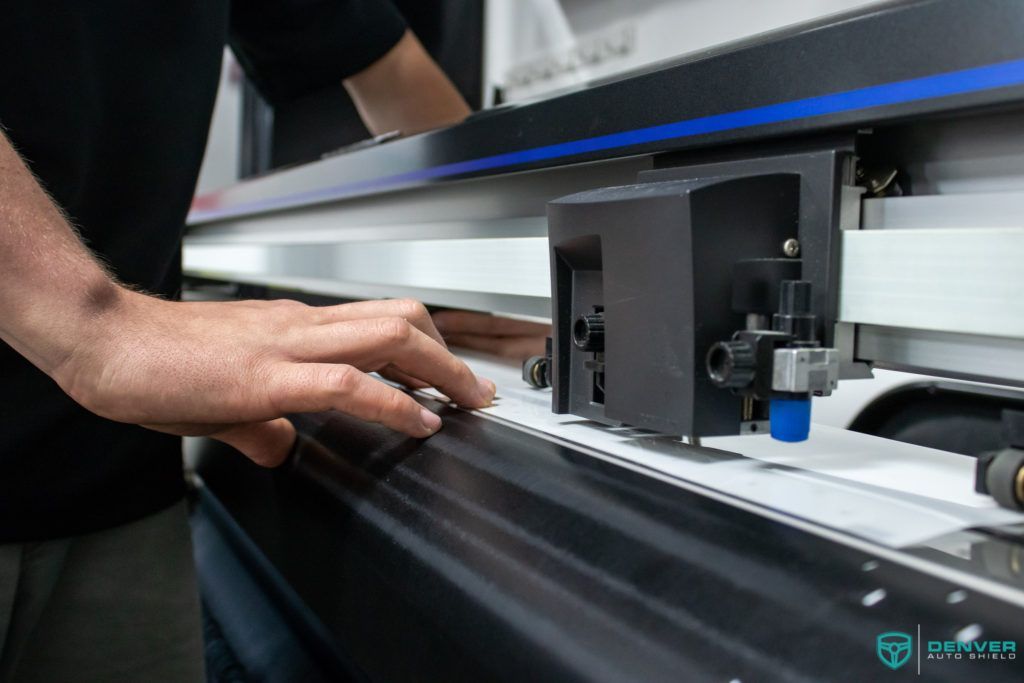 A man is using a machine to cut a piece of paper.