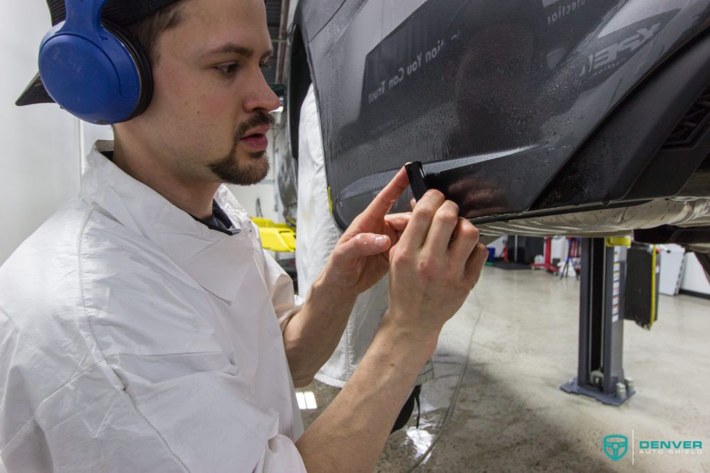 A man wearing headphones is working on a car in a garage.