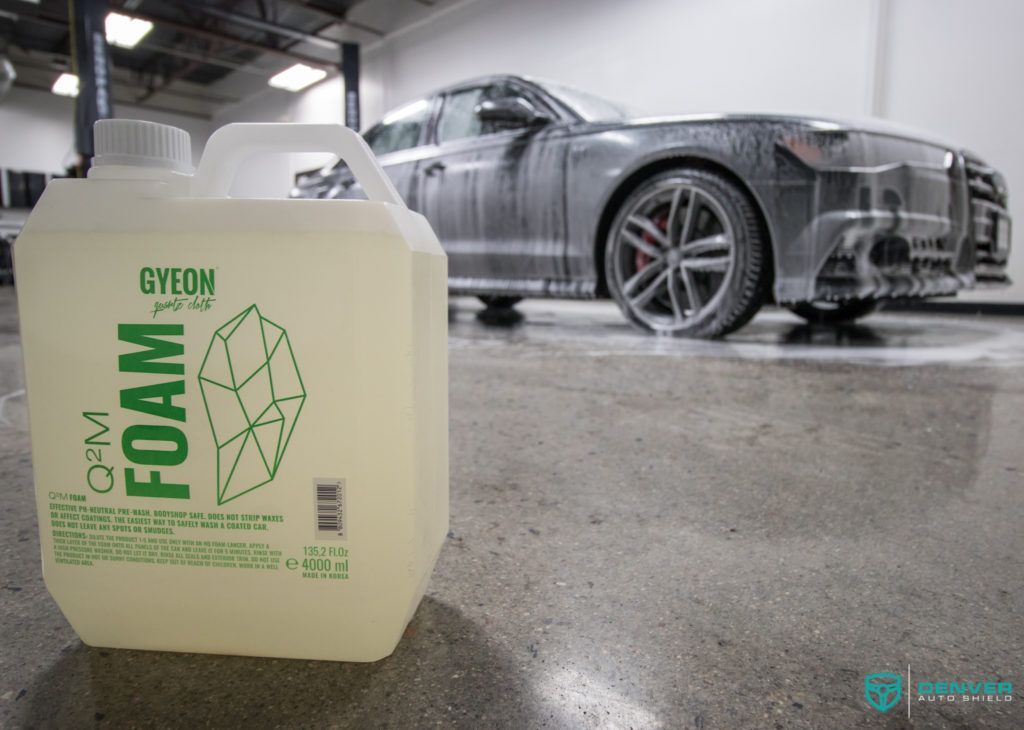 A bottle of foam is sitting next to a car in a garage.