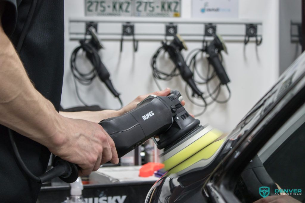 A man is polishing a car with a husky polisher