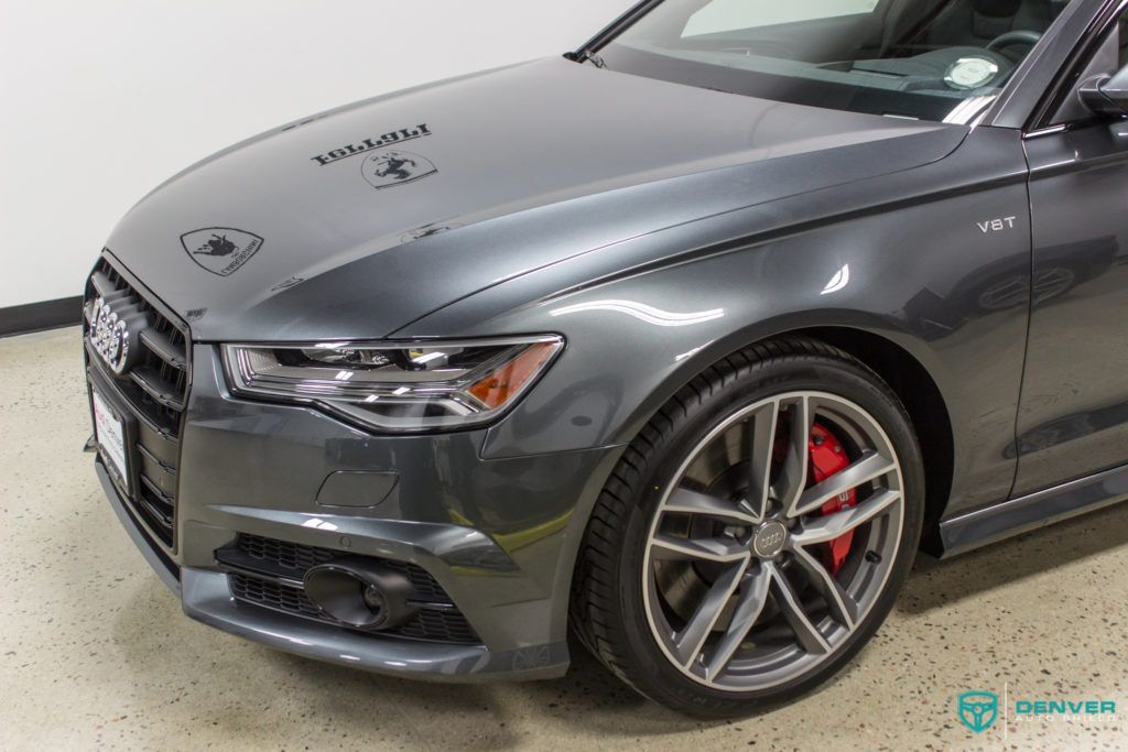 A gray audi a6 with red brake calipers is parked in a garage.