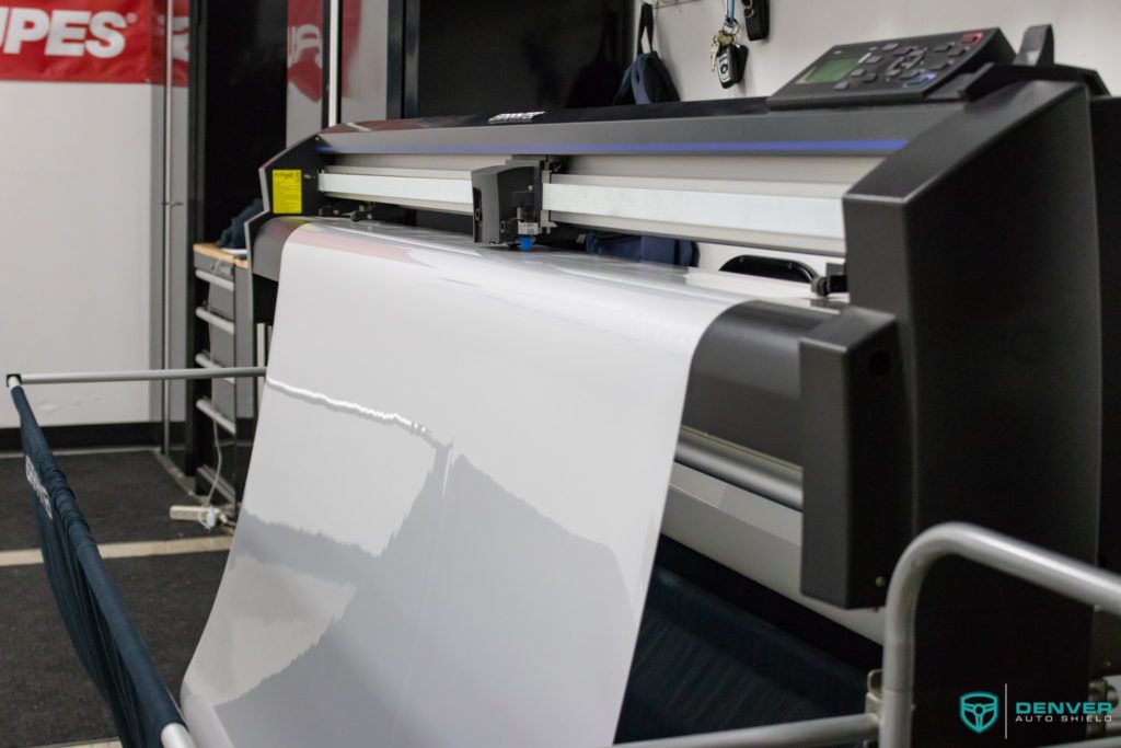 A large printer is printing a large piece of paper