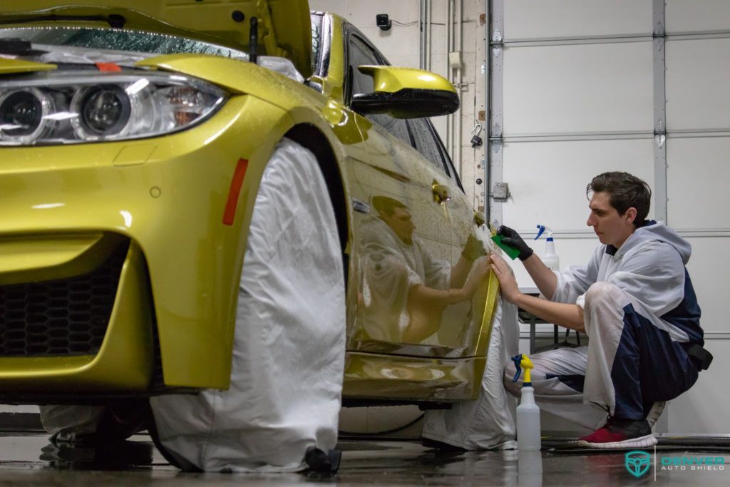 A man is cleaning a yellow car in a garage.