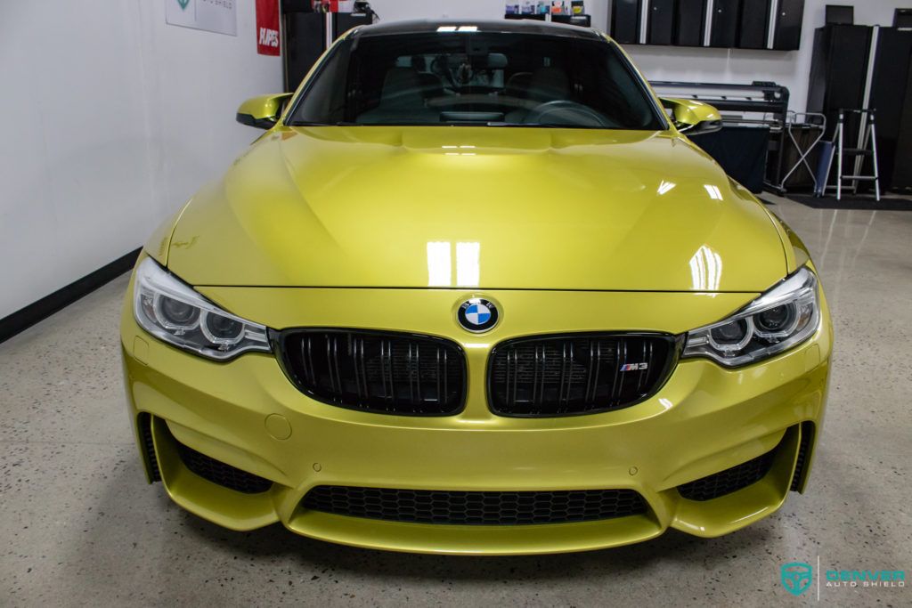 A yellow bmw m4 is parked in a garage.