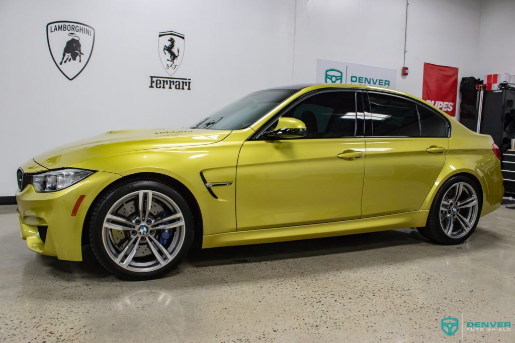 A yellow bmw m3 is parked in a garage.