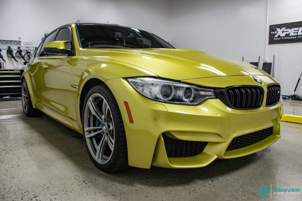 A yellow bmw m4 is parked in a garage.