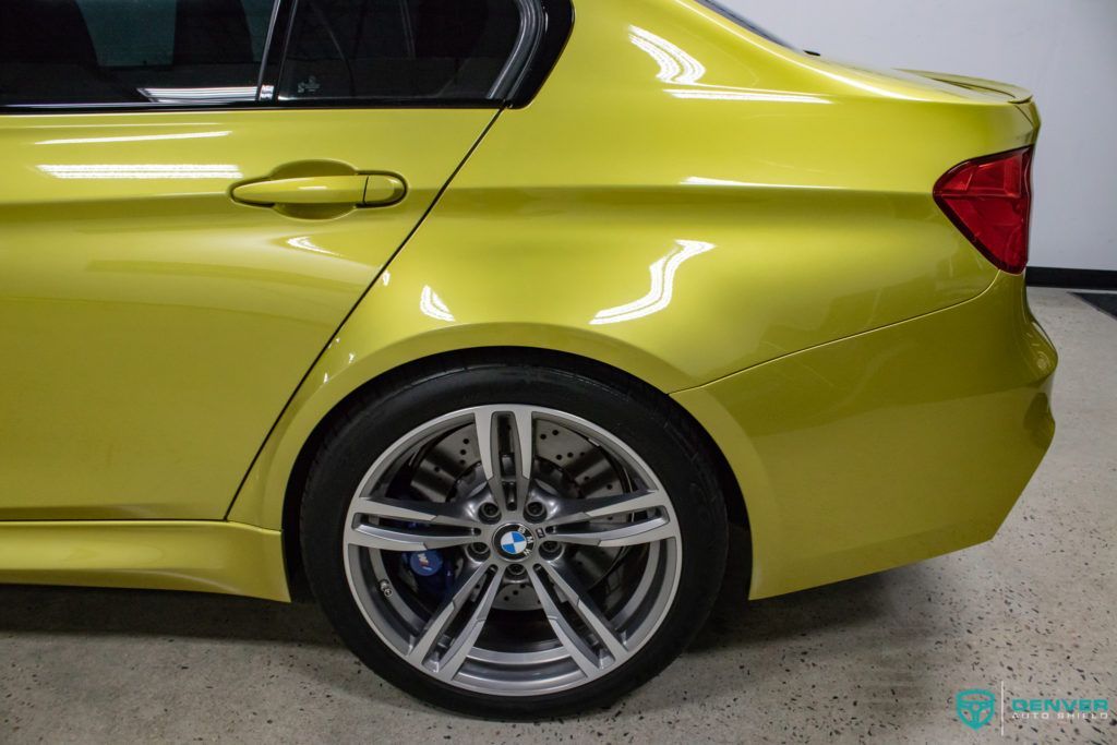 A yellow bmw m3 is parked in a garage.