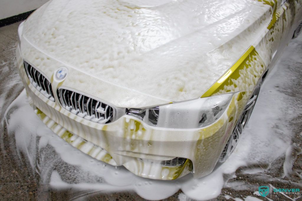 A car is covered in foam and is sitting on the floor.