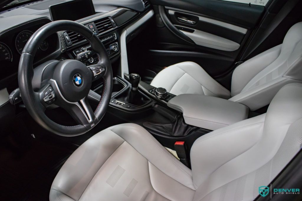 The interior of a bmw m3 with white leather seats and a steering wheel.