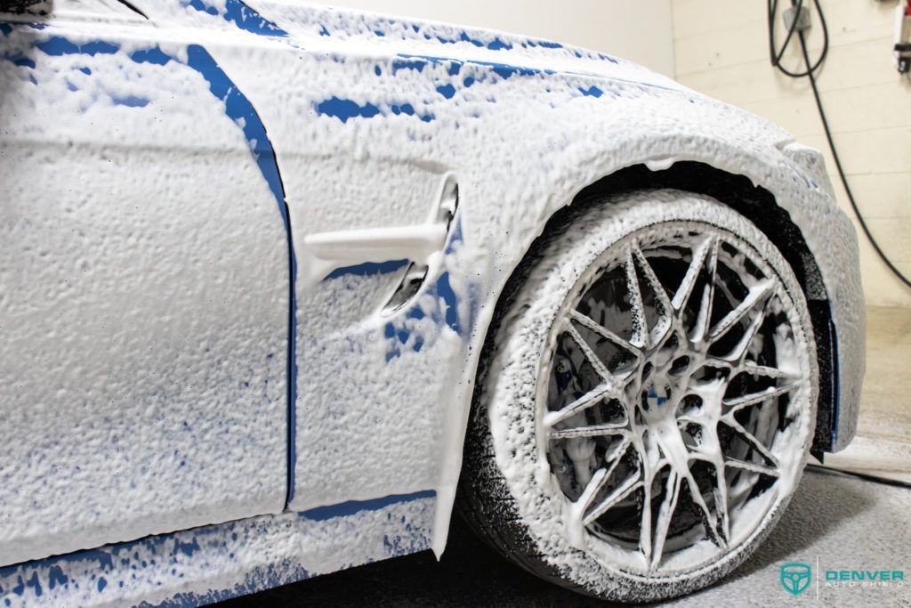 A white car is covered in foam and soap.