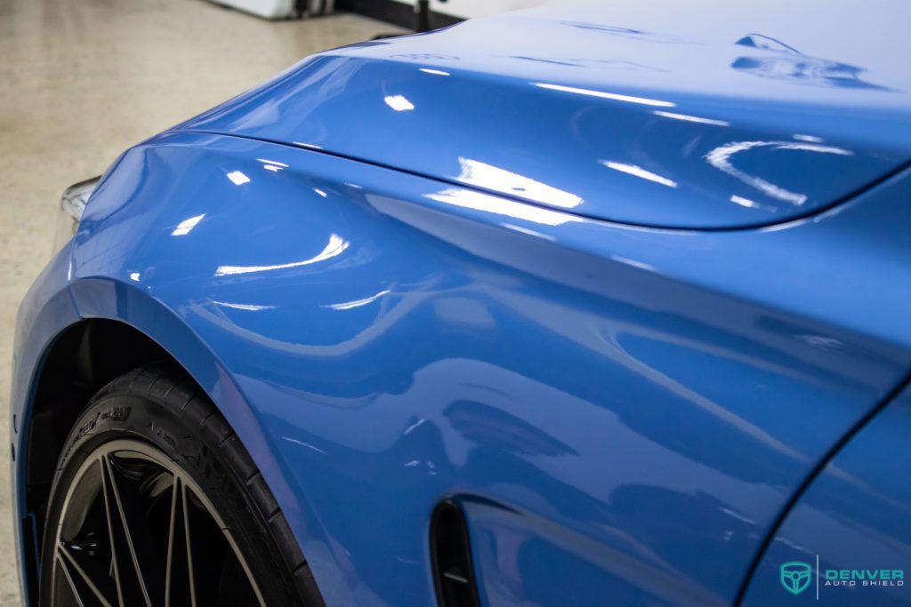 A close up of a blue car 's fender in a garage.