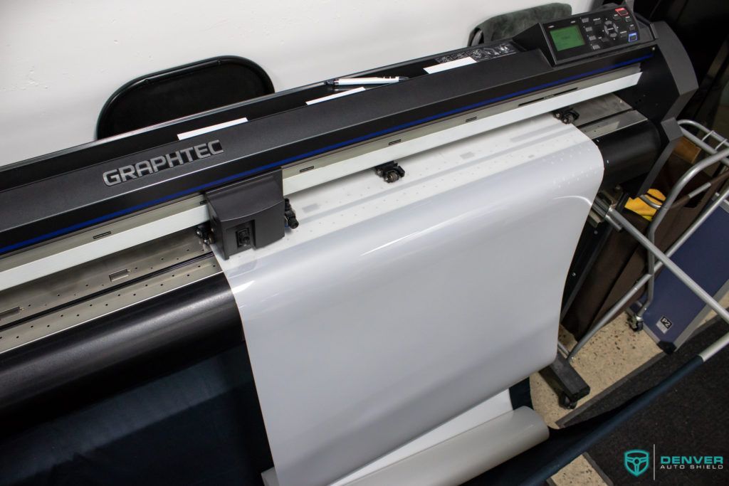 A large printer is printing a large piece of paper.