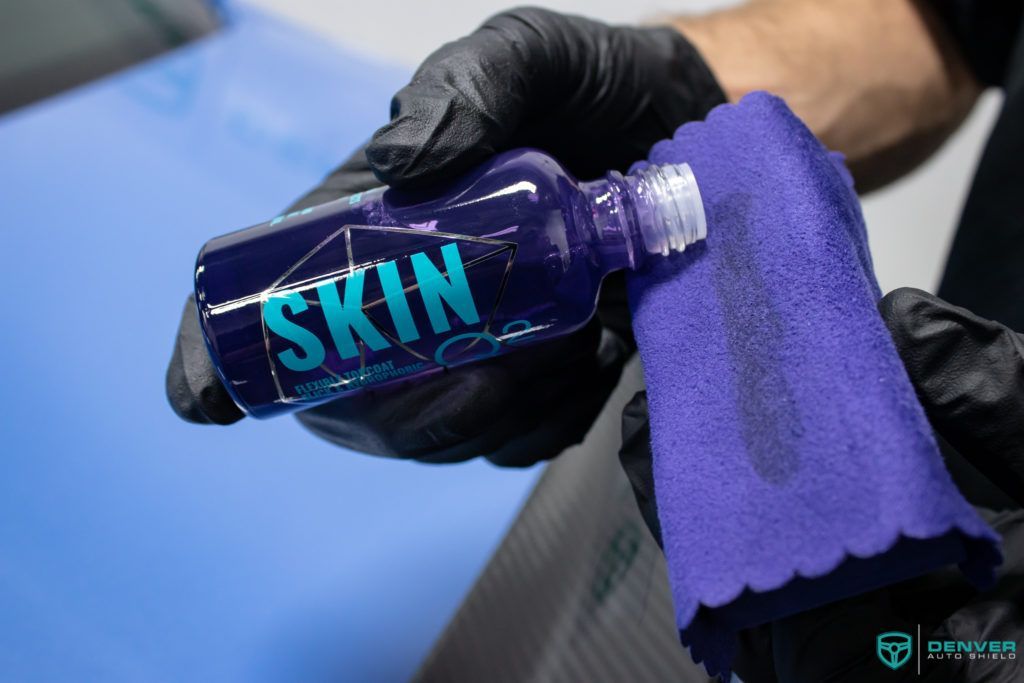 A person is holding a bottle of skin and a towel.