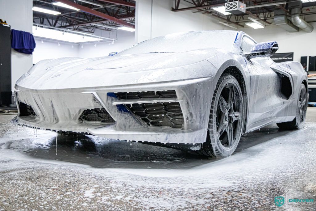 A sports car is covered in foam in a garage.