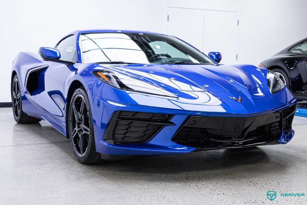 A blue sports car is parked in a garage next to another car.