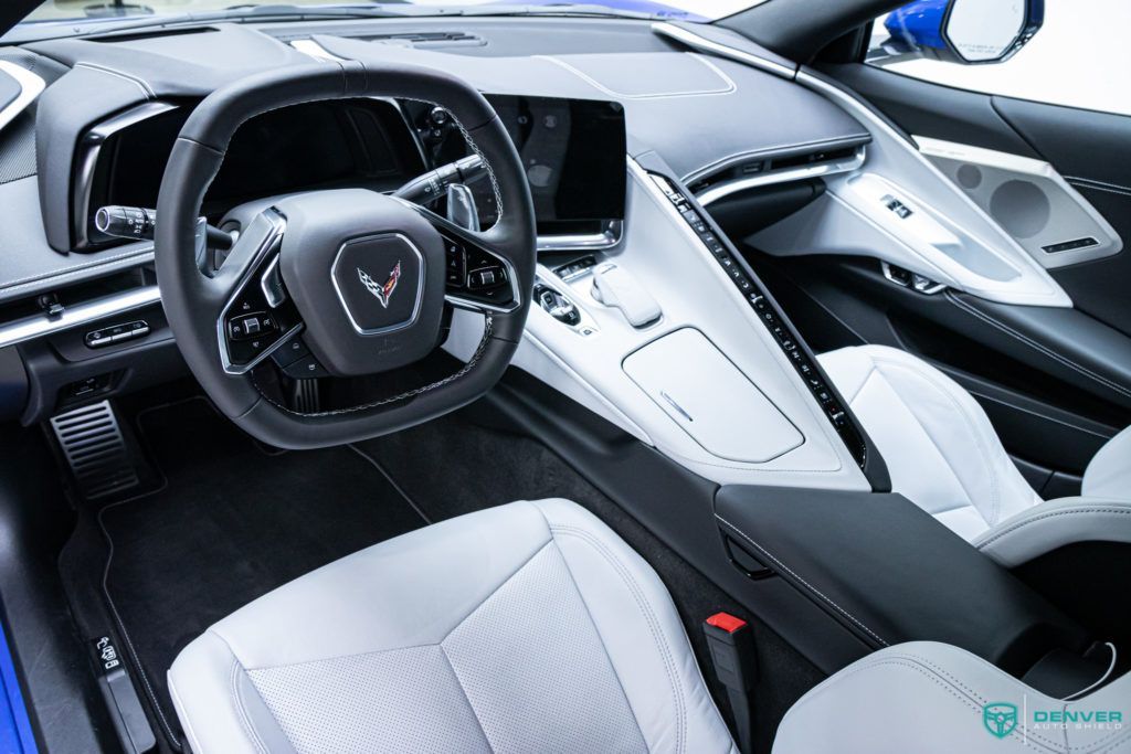 The interior of a blue sports car with white seats and a steering wheel.