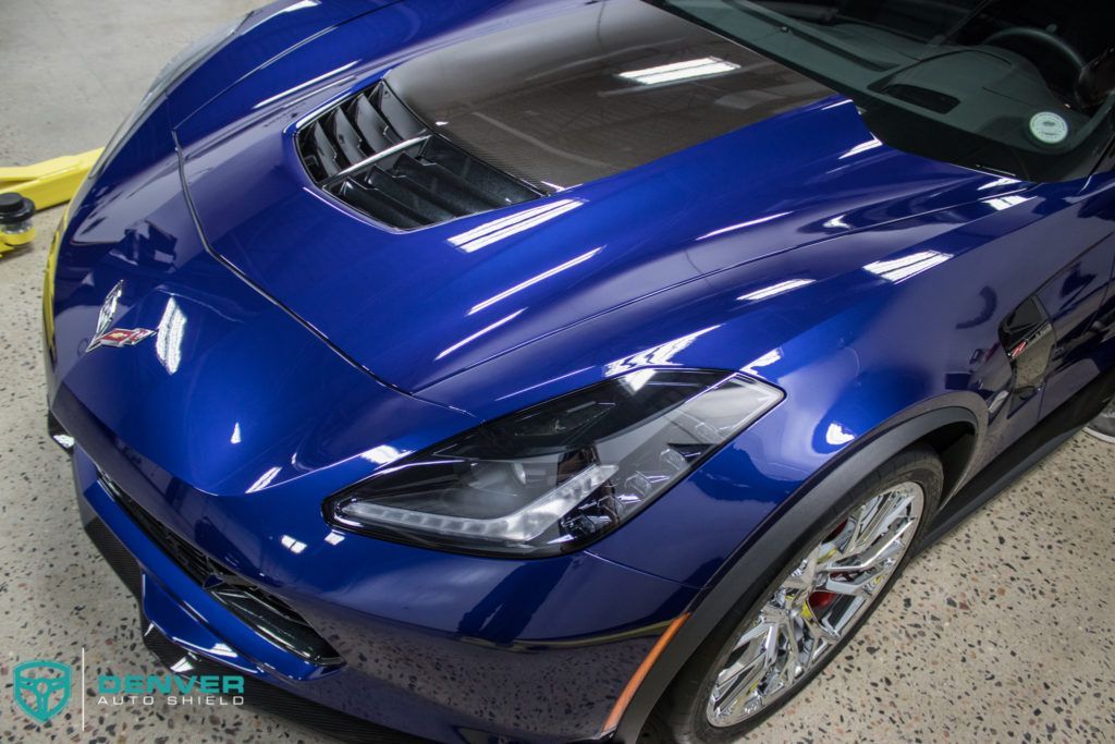 A blue sports car with a black hood is sitting in a garage