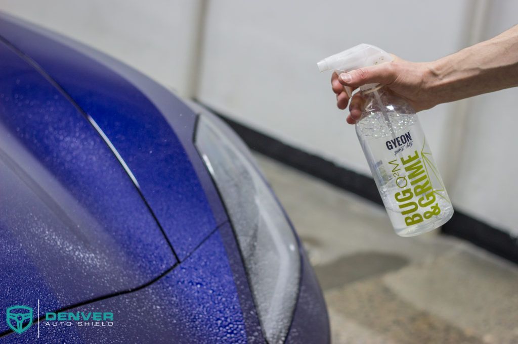 A person is spraying a car with a spray bottle.