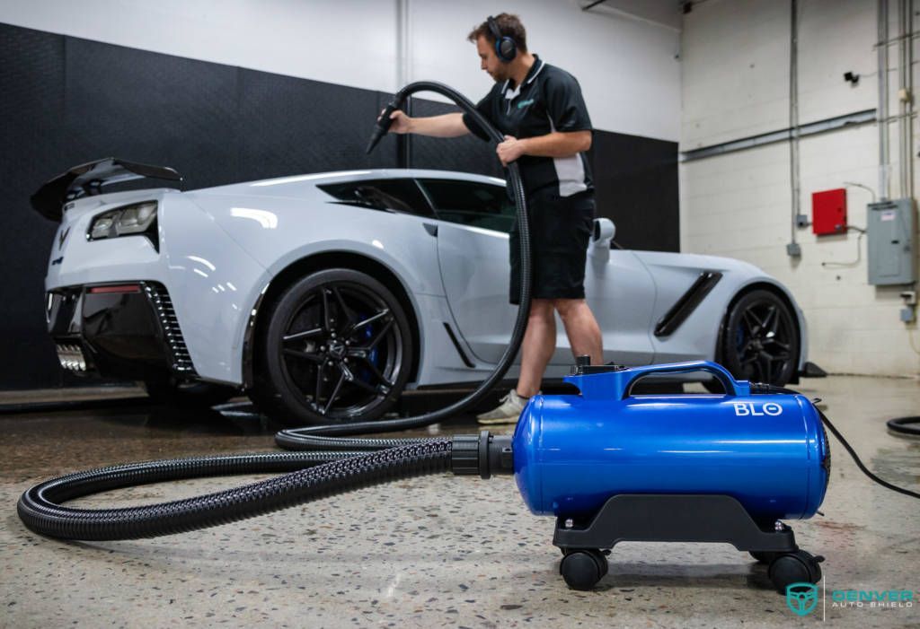 A man is cleaning a car with a vacuum cleaner in a garage.