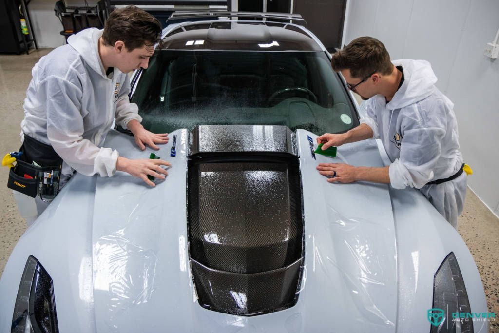 Two men are working on a car in a garage.