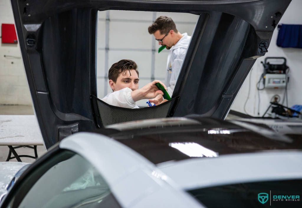 Two men are working on a car in a garage.