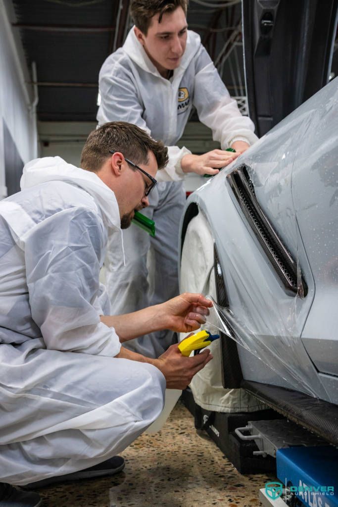 Two men are working on a car in a garage.