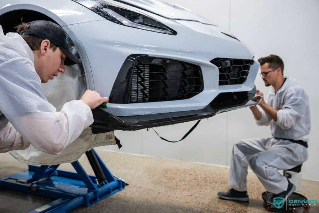 Two men are working on a car in a garage.