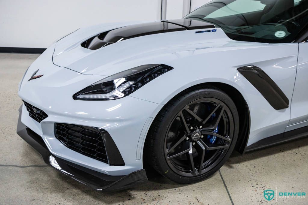 A white sports car with black wheels is parked in a garage.