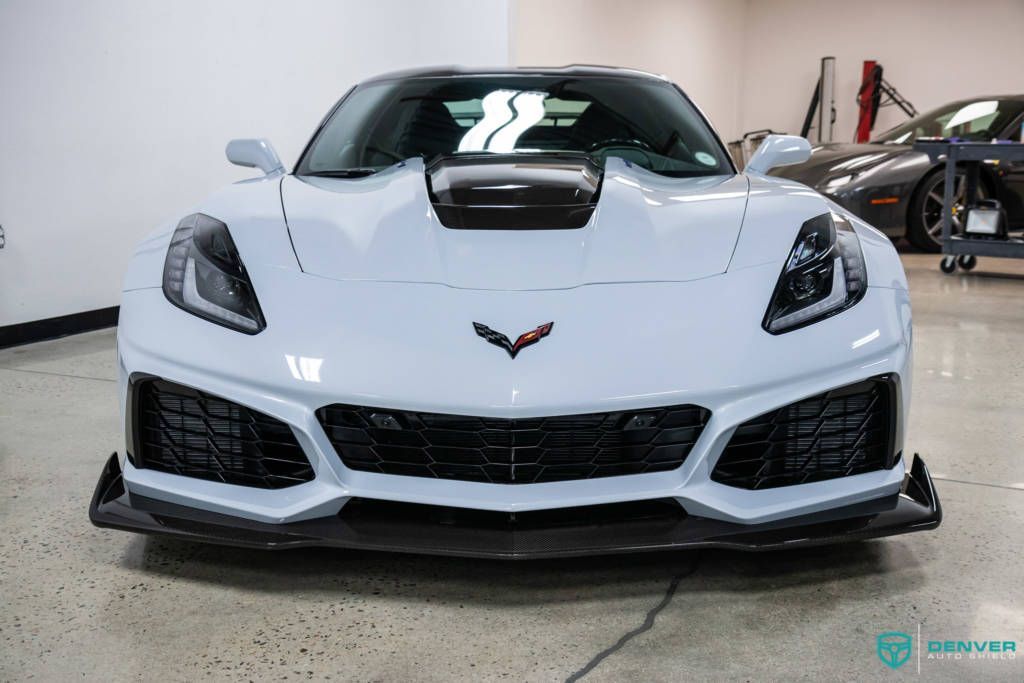 A white corvette is parked in a garage.