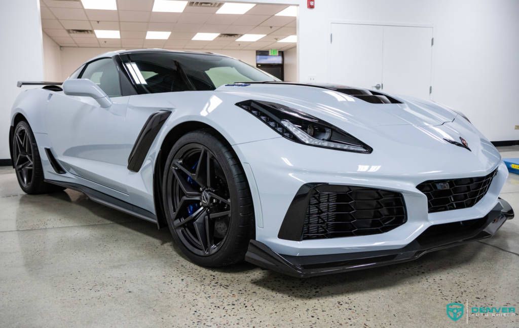 A white corvette zr1 is parked in a showroom.