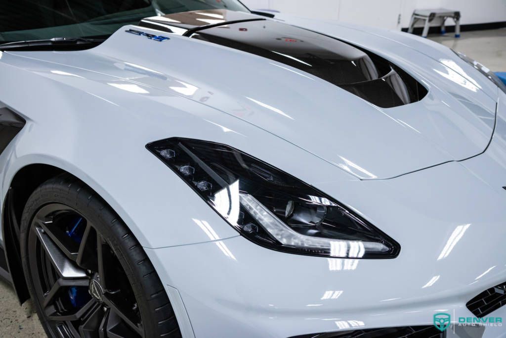 A white sports car with black wheels is parked in a garage.