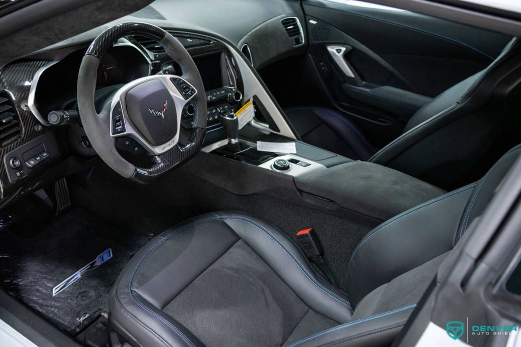 The interior of a white sports car with black seats and a steering wheel.