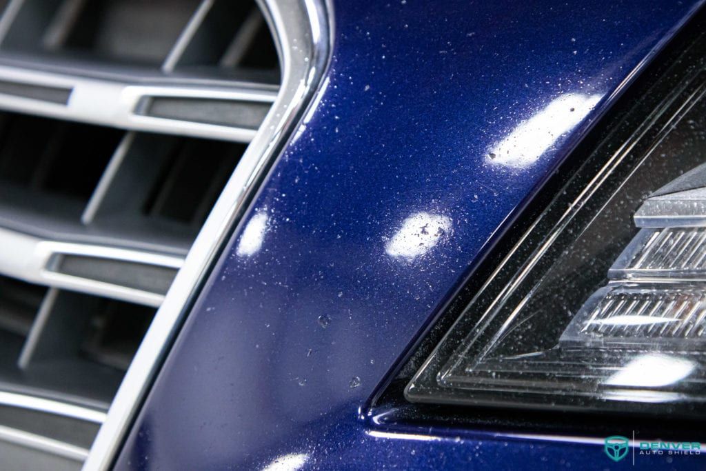 A close up of a blue car 's headlight and grille